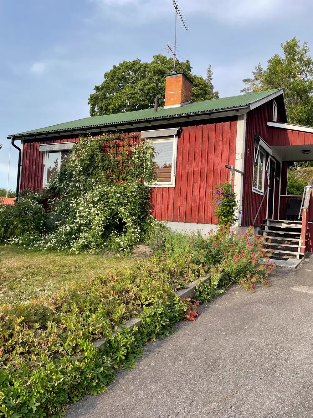 Rotes Ferienhaus in Ankarsrum mit grünem Dach und blühendem Vorgarten