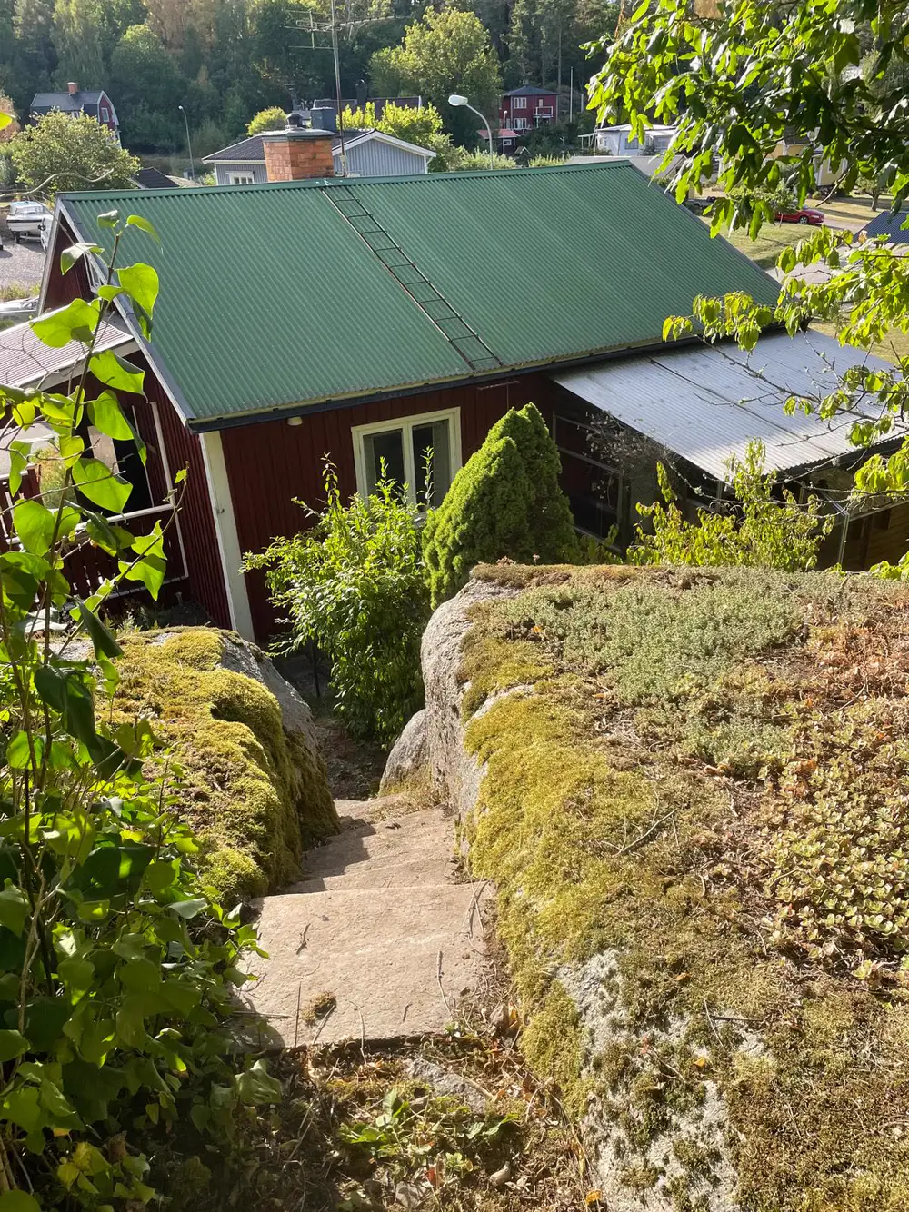 Blick vom Felsen im Garten auf das Ferienhaus mit grünem Dach
