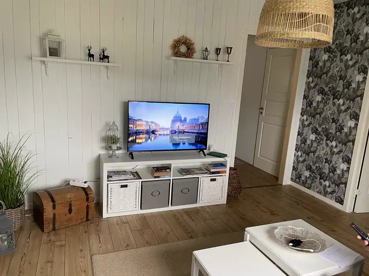 Wohnzimmer mit Fernseher und weißer Holzwand